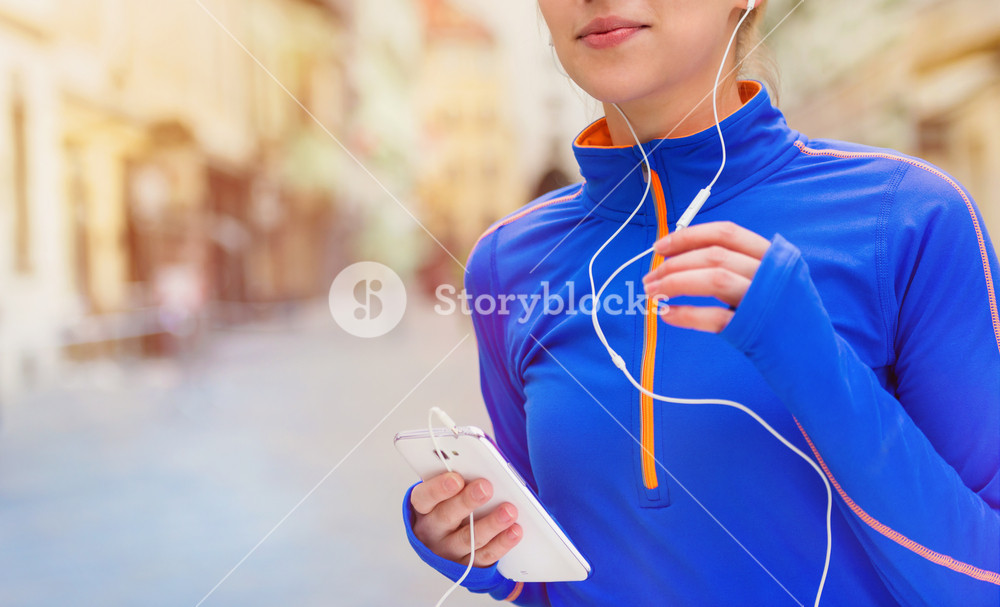 Young woman running in city competition, enjoying the music