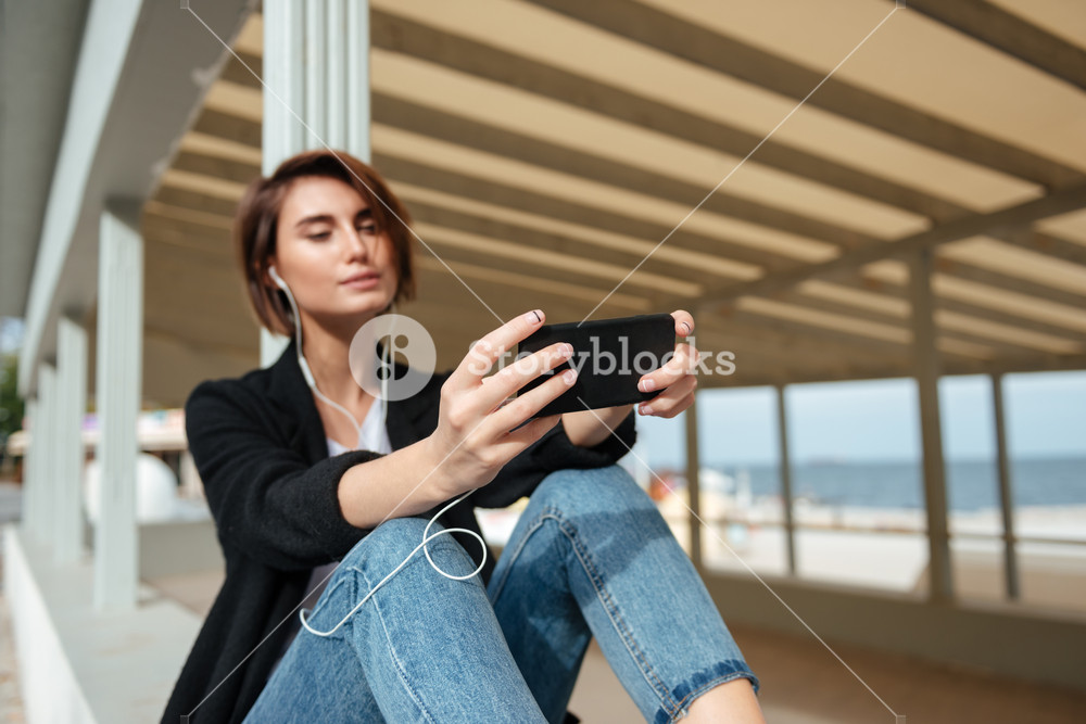 Young woman enjoying music on the beach verandah