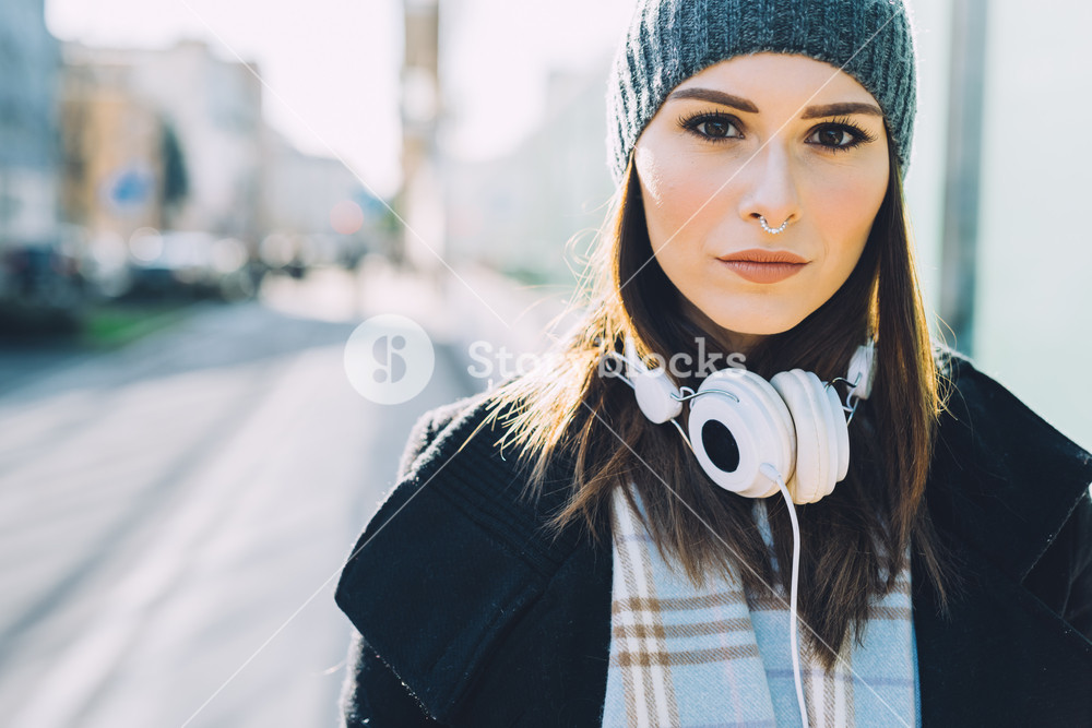 Young woman in the city with headphones, listening to music, looking serious - happiness, relaxing, technology concept