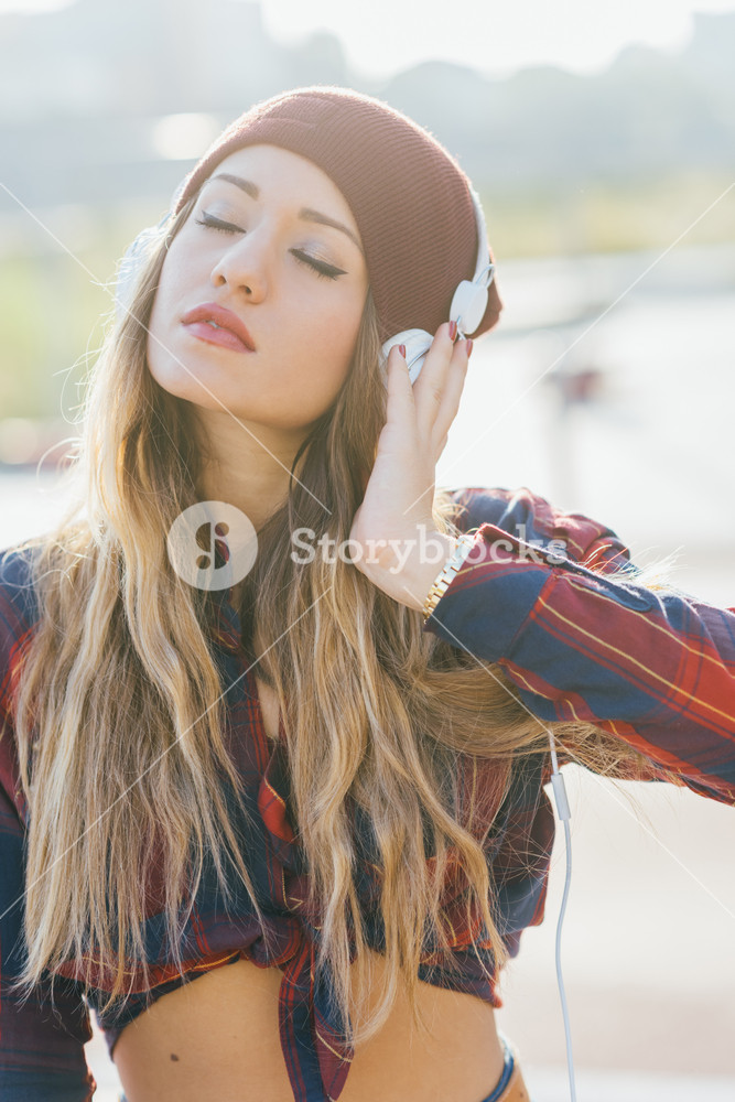 Young woman listening to music with headphones, deep in thought - music, technology, future concept