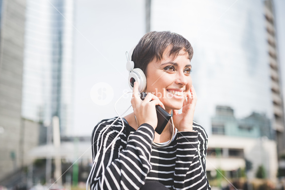 Half length portrait of young woman listening to music with headphones and smartphone, smiling - music, relax, technology concept