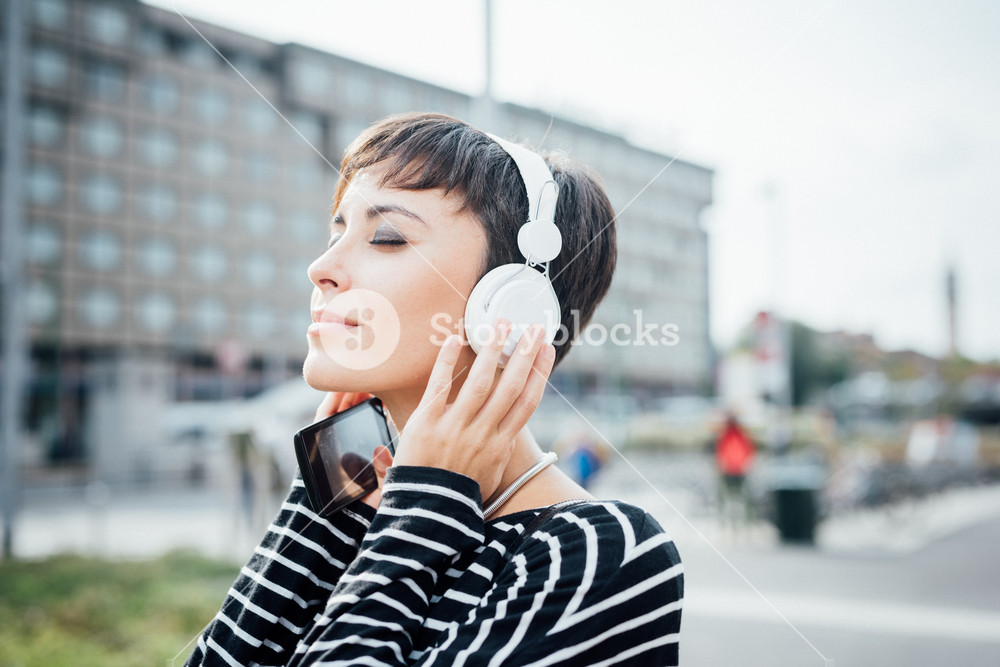 Half length portrait of young woman listening to music with headphones and smartphone, smiling - music, relax, technology concept