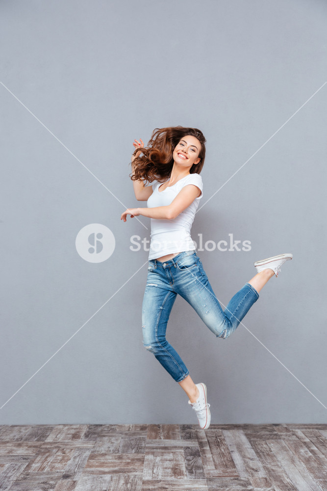 Joyful young woman in white outfit jumping Royalty-Free Stock Photo SBI ...