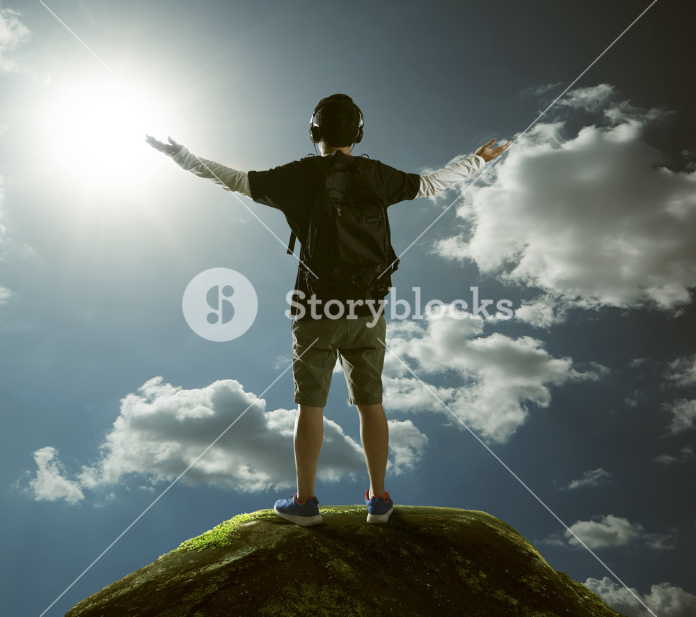 Hiker with backpack standing on top of a mountain with raised hands and ...