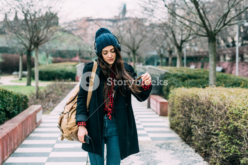 Young woman walking in the city, enjoying music with headphones and smartphone - technology, music, relaxation
