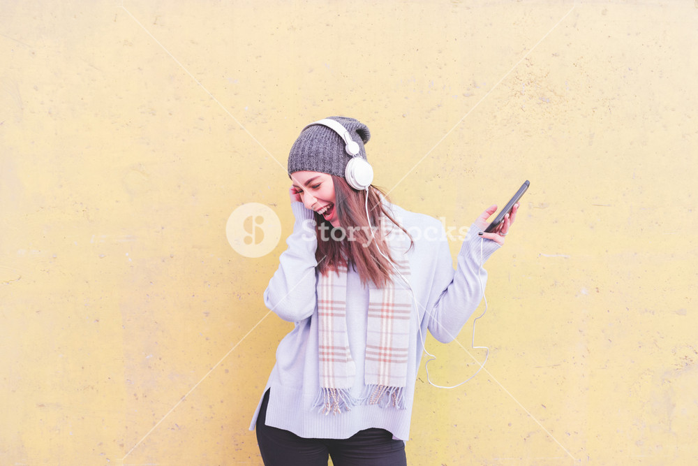 Figure of young woman listening to music with headphones and smartphone, dancing - music, happiness, dancing concept