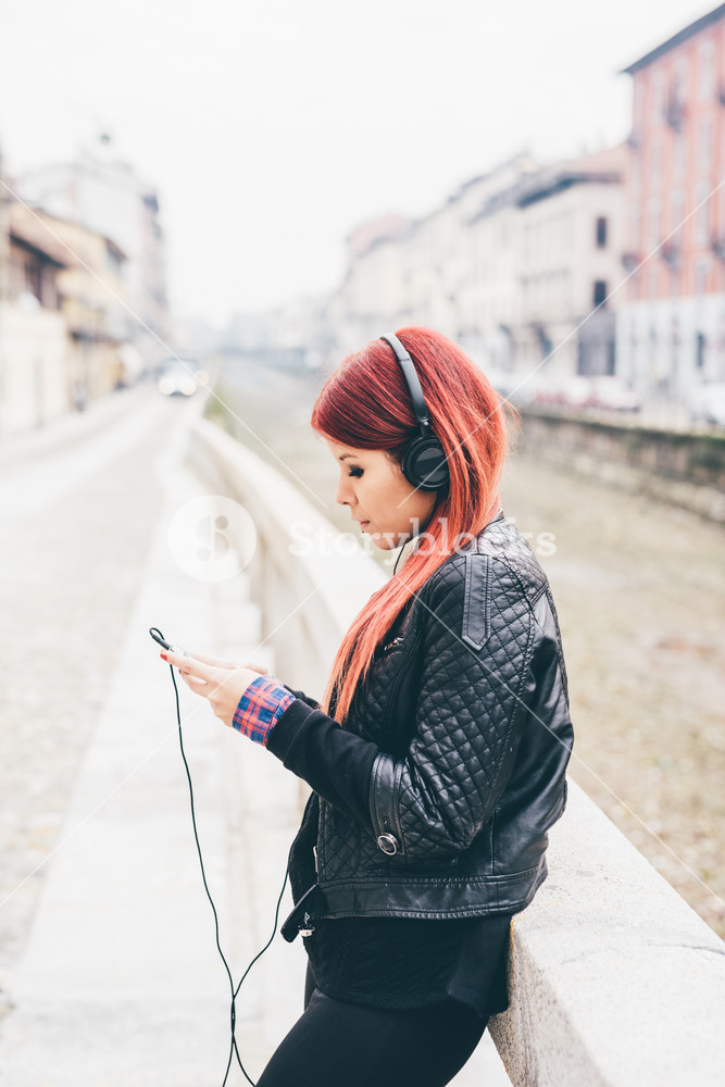 Young woman enjoying music outdoors with headphones and smartphone - technology, music, social concept