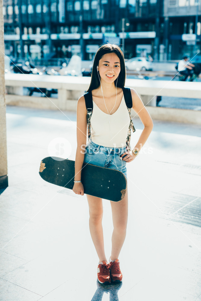 Young Asian woman skater enjoying music, smiling - sportive, music, happiness, relaxing concept