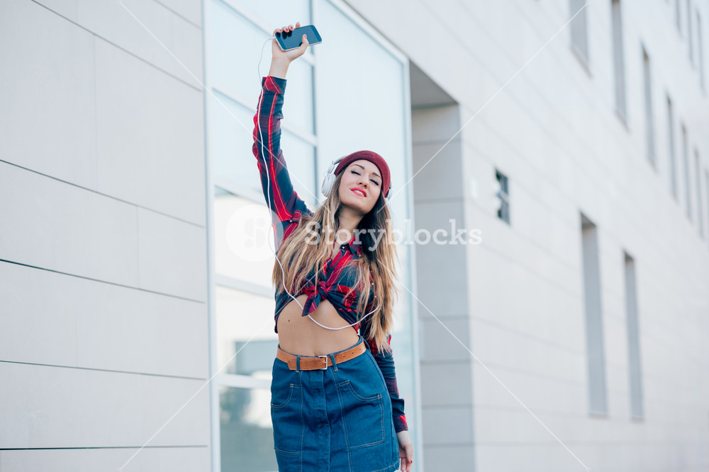 Young woman enjoying music with headphones and smartphone - freedom, music, technology concept