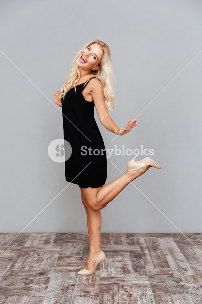 Elegant young woman in black dress posing on one leg, isolated on gray  background Royalty-Free Stock Photo SBI-302775742 - Storyblocks