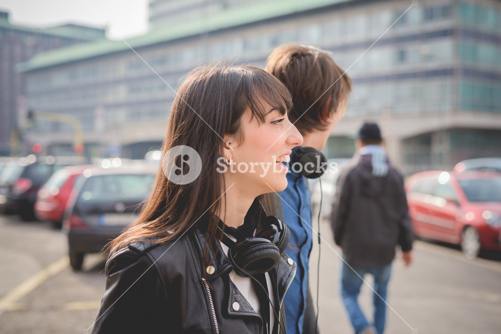 Portrait of a young couple with a skate and moustache, enjoying the streets while listening to music - carefreeness, friendship, love concept
