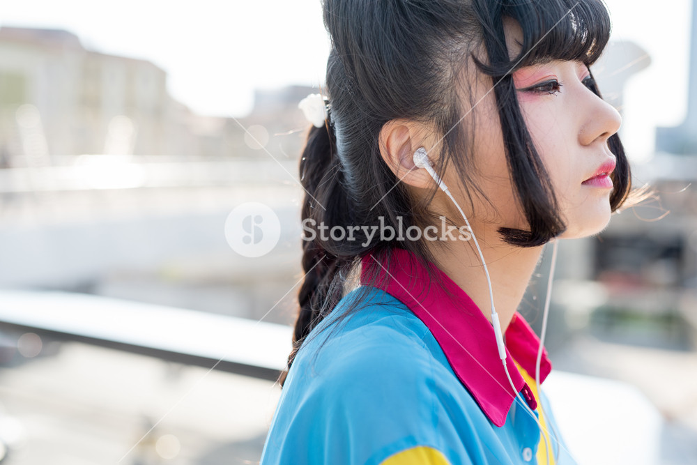 Portrait of young beautiful woman listening to music outdoors in the city - relaxing, music, technology concept