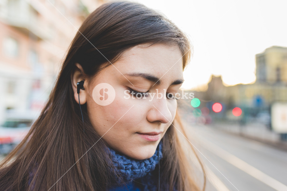 Portrait of a young beautiful woman enjoying music outdoors in the city - music, relaxation, technology concept