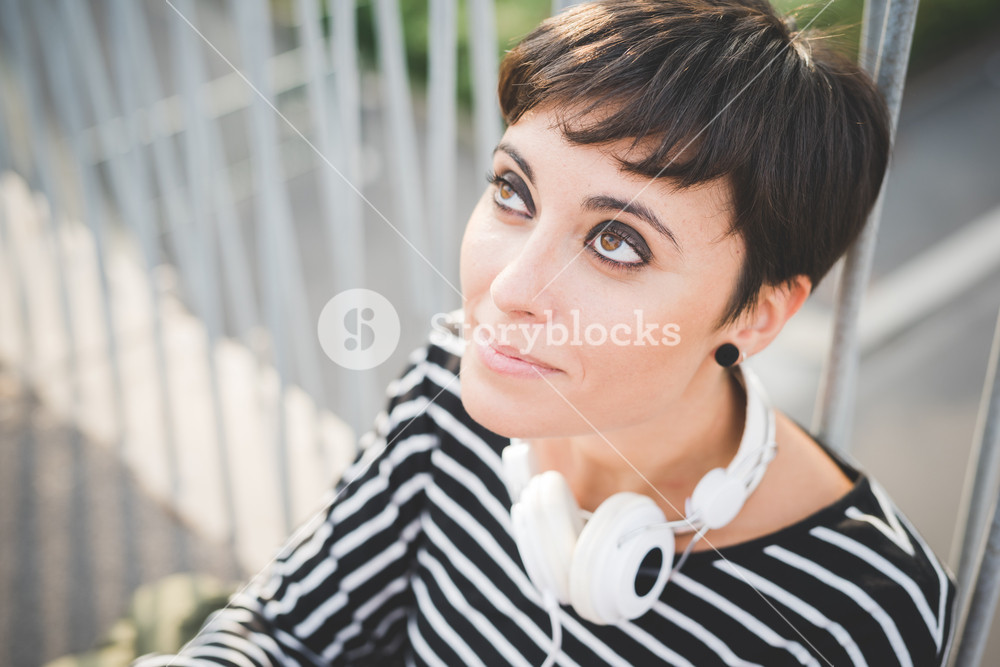 Portrait of young woman listening to music with headphones, deep in thought - music, relaxation, contemplation