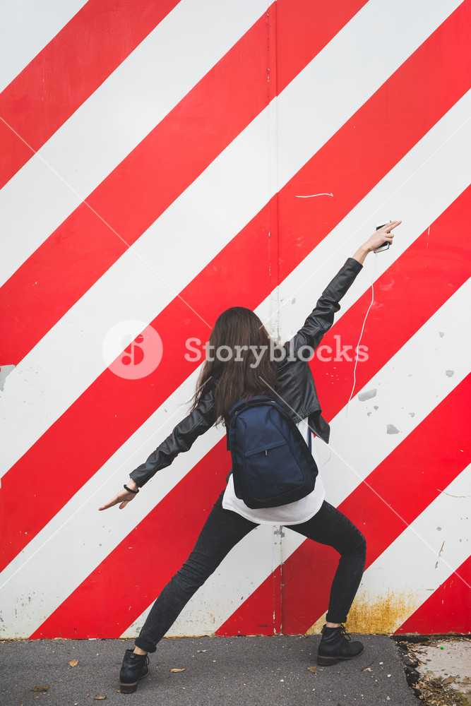 Rear view of stylish Asian woman enjoying music and dancing in the city - music, fun, dancing concept