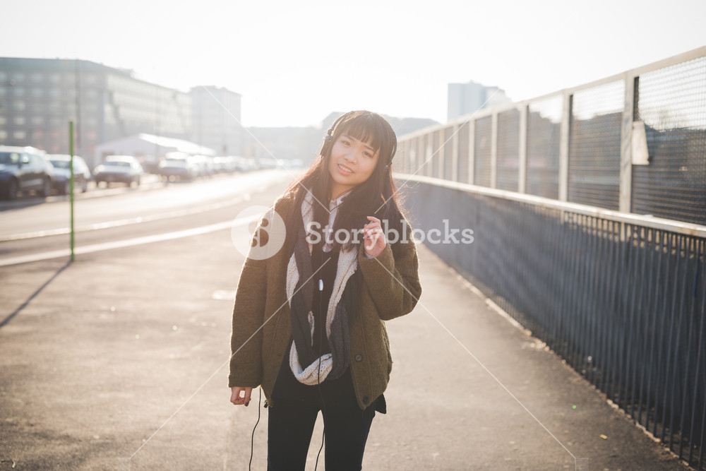 Young woman enjoying cityscape at sunset, listening to music