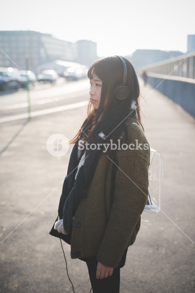 Young woman enjoying cityscape at sunset, listening to music