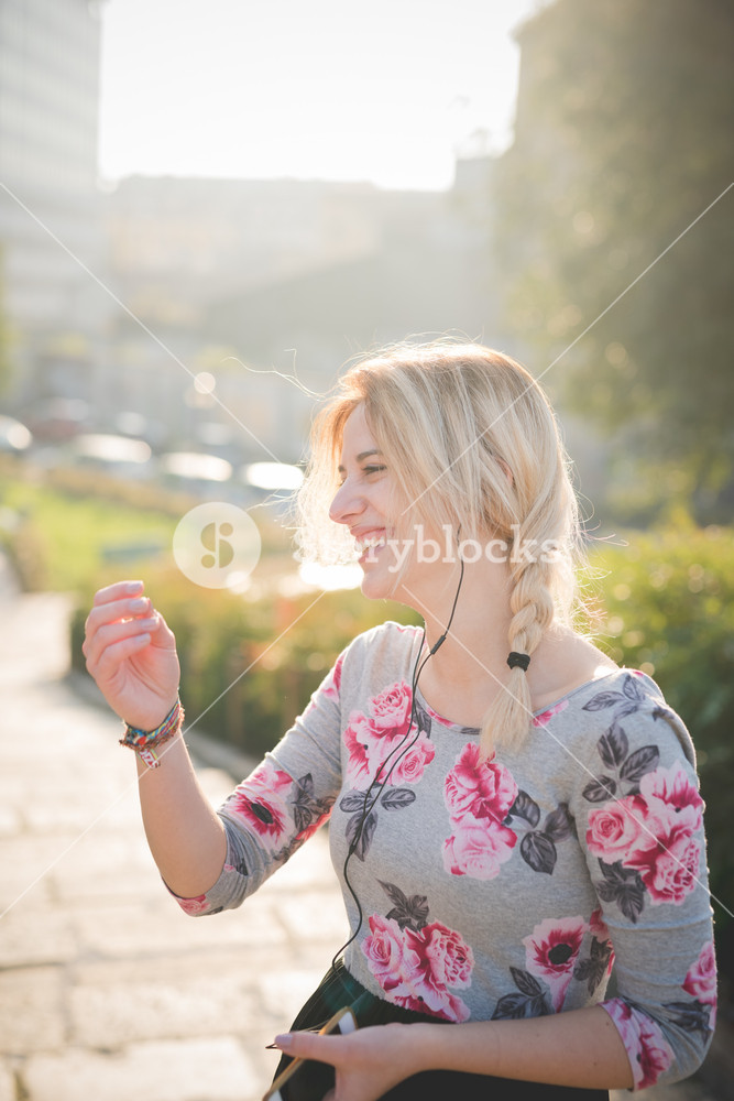 Young woman enjoying music and using smartphone outdoors in the city