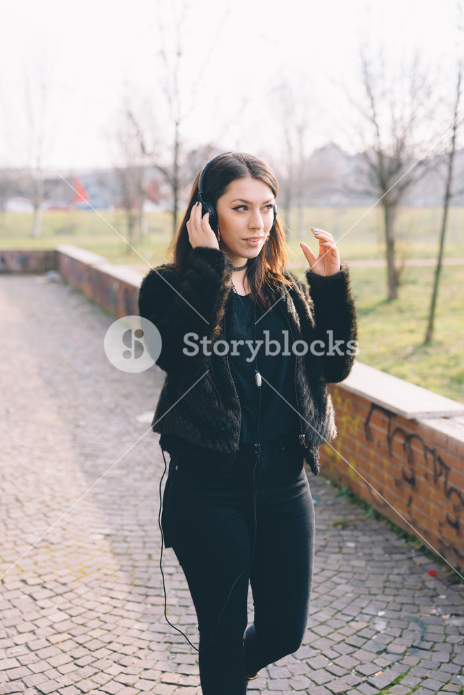 Young woman enjoying music with headphones in a city park - music, relaxation, serenity concept