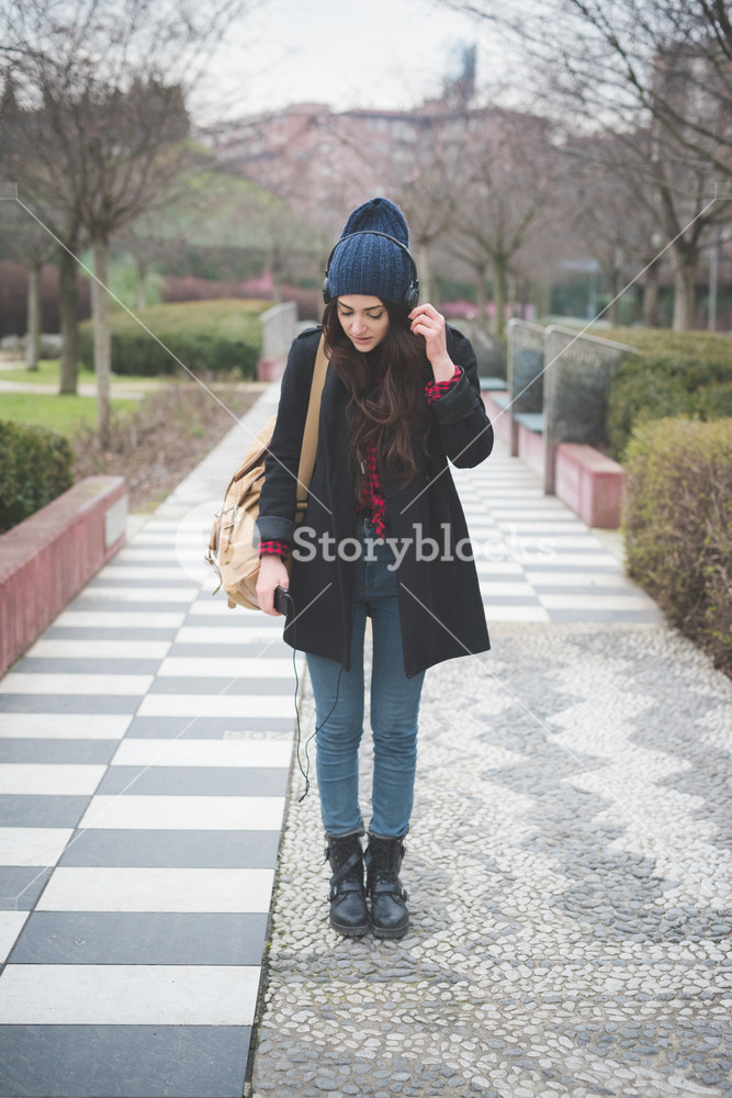 Young woman enjoying music while walking through the city - carefree and relaxed