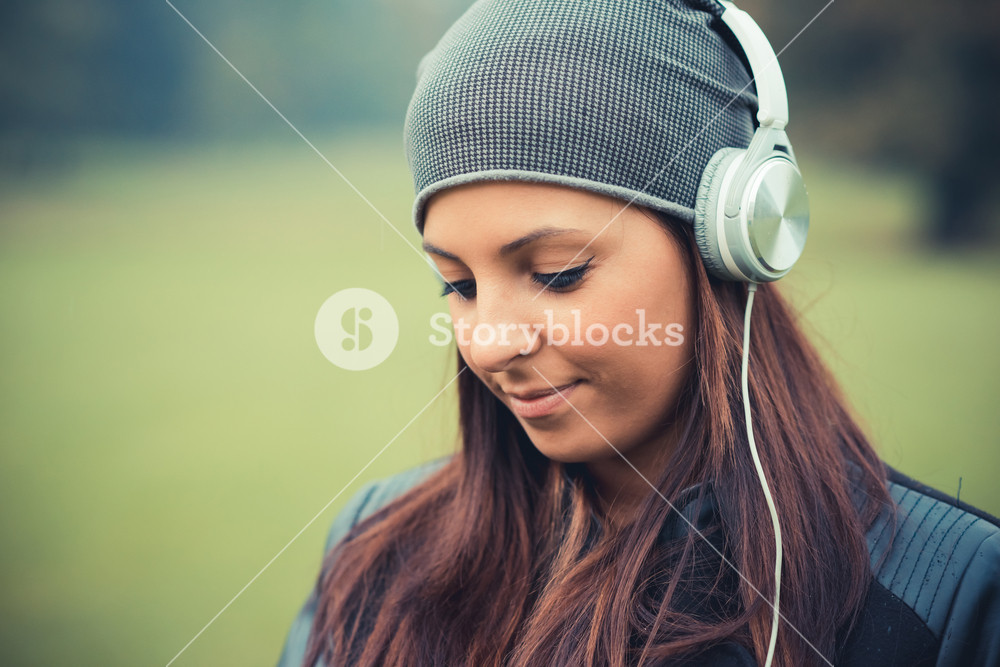 Beautiful woman enjoying music in the park during autumn season