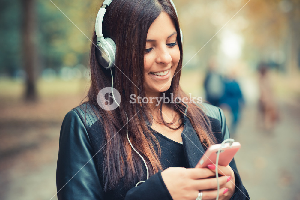 Autumn Park: Young Woman Enjoying Music with Headphones and Smartphone