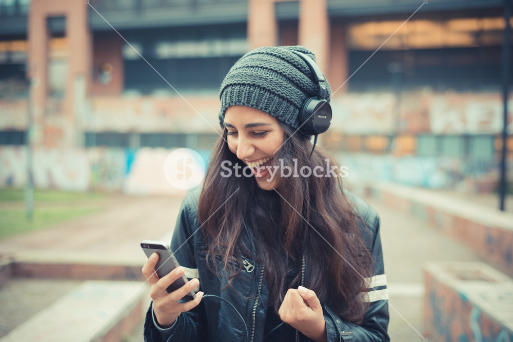 Stylish woman enjoying music with headphones in the city