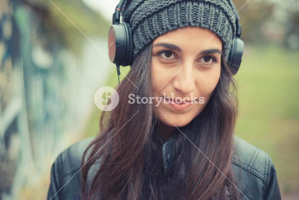 Stylish woman enjoying music with headphones in the city