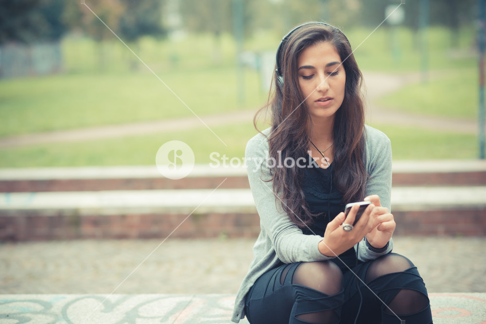 Stylish woman enjoying music with headphones in the city