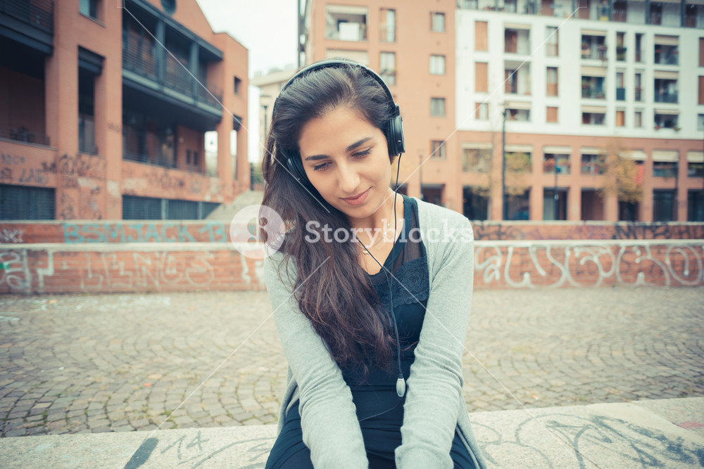 Stylish woman enjoying music with headphones in the city