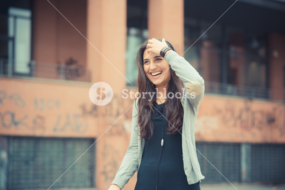Stylish woman enjoying music with headphones in the city