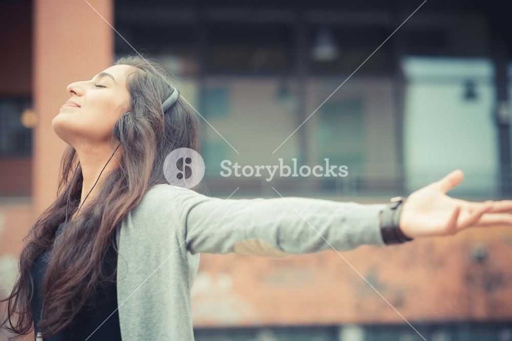 Stylish woman enjoying music with headphones in the city
