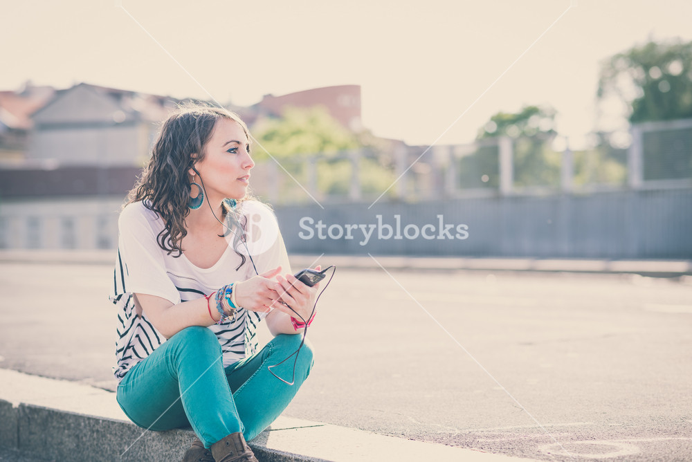Young woman enjoying music with smartphone in the city