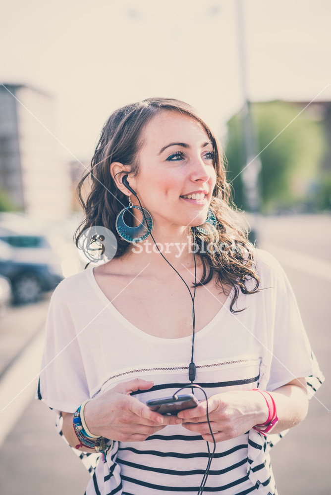 Young woman enjoying music with smartphone in the city