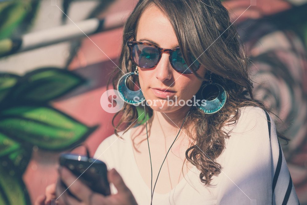 Young woman enjoying music with smartphone in the city