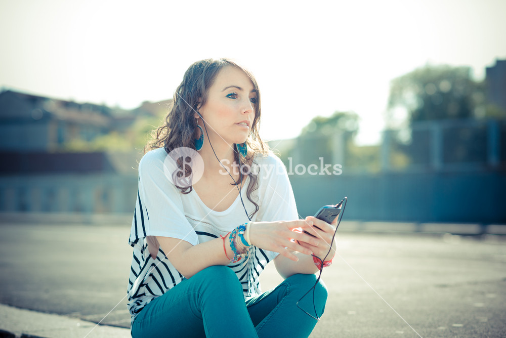 Young woman enjoying music with smartphone in the city