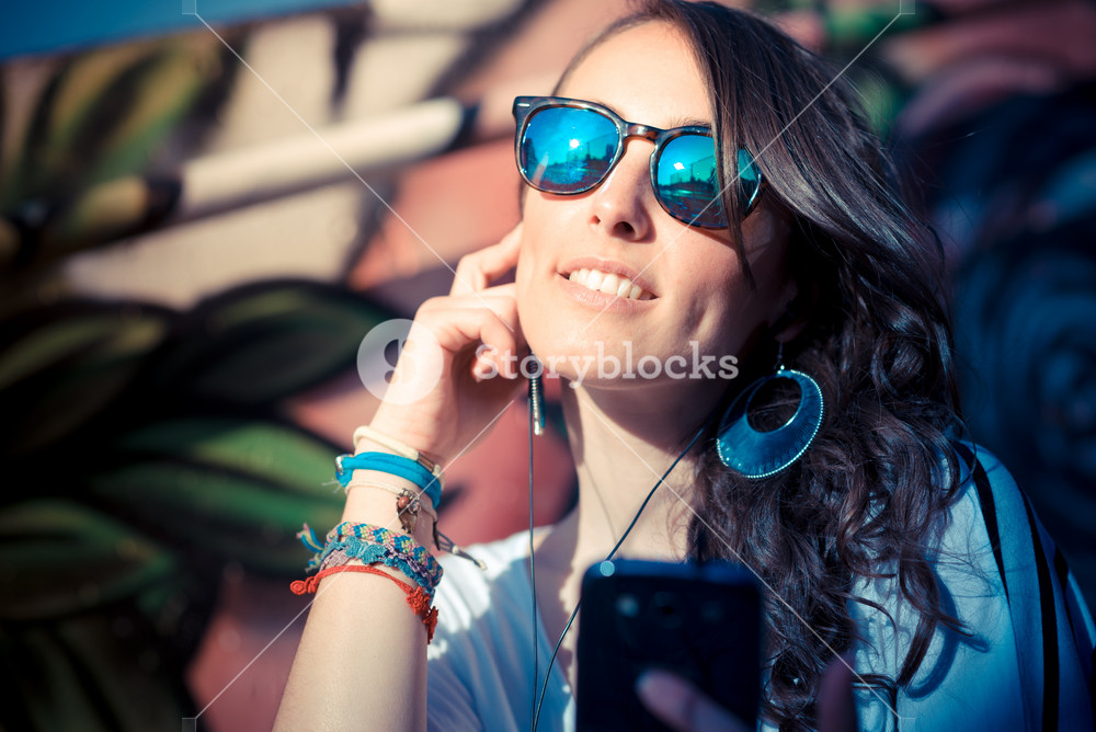 Young woman enjoying music with smartphone in the city