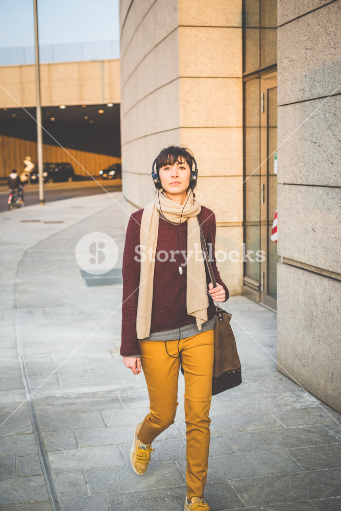 Stylish woman enjoying music with headphones in the city