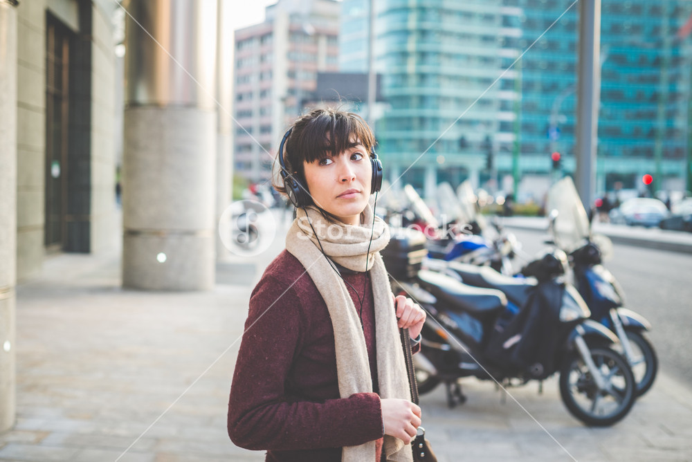 Stylish woman enjoying music with headphones in the city