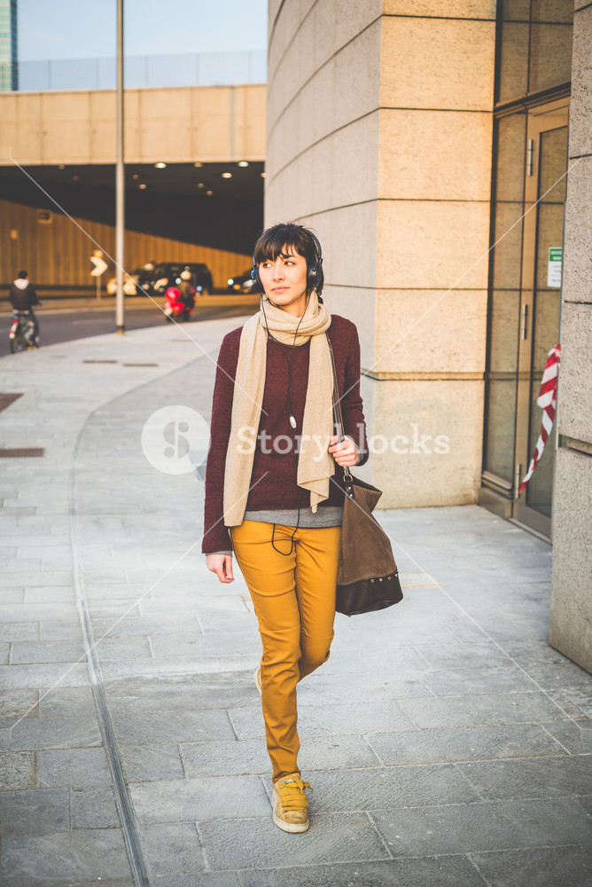 Stylish woman enjoying music with headphones in the city