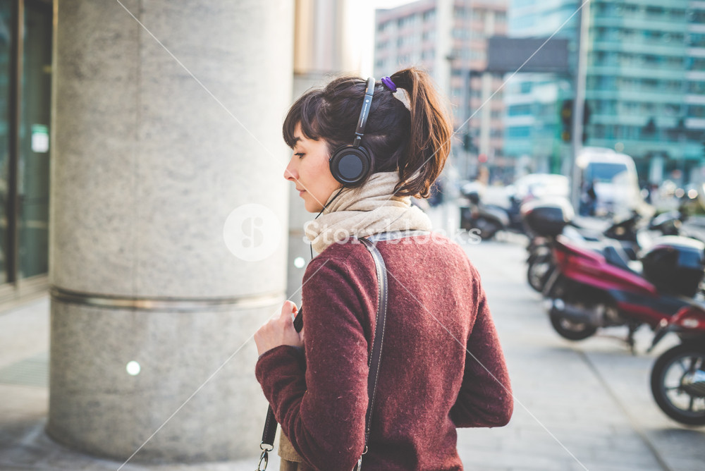 Stylish woman enjoying music with headphones in the city
