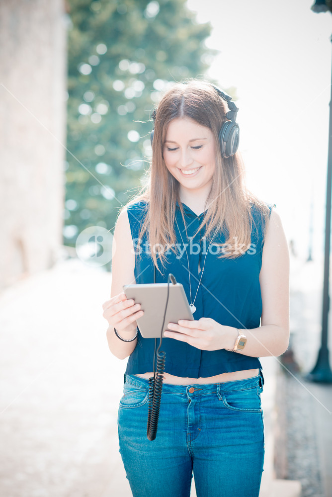 Stylish woman enjoying music with headphones in the city