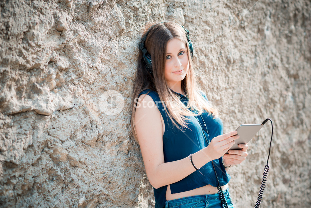 Stylish woman enjoying music with headphones in the city