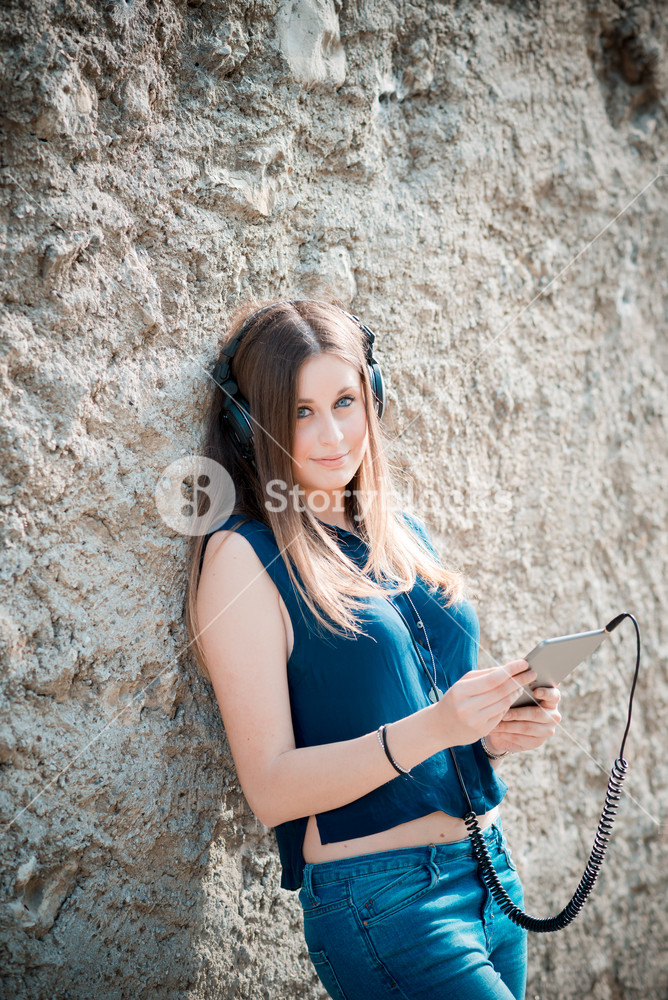 Stylish woman enjoying music with headphones in the city