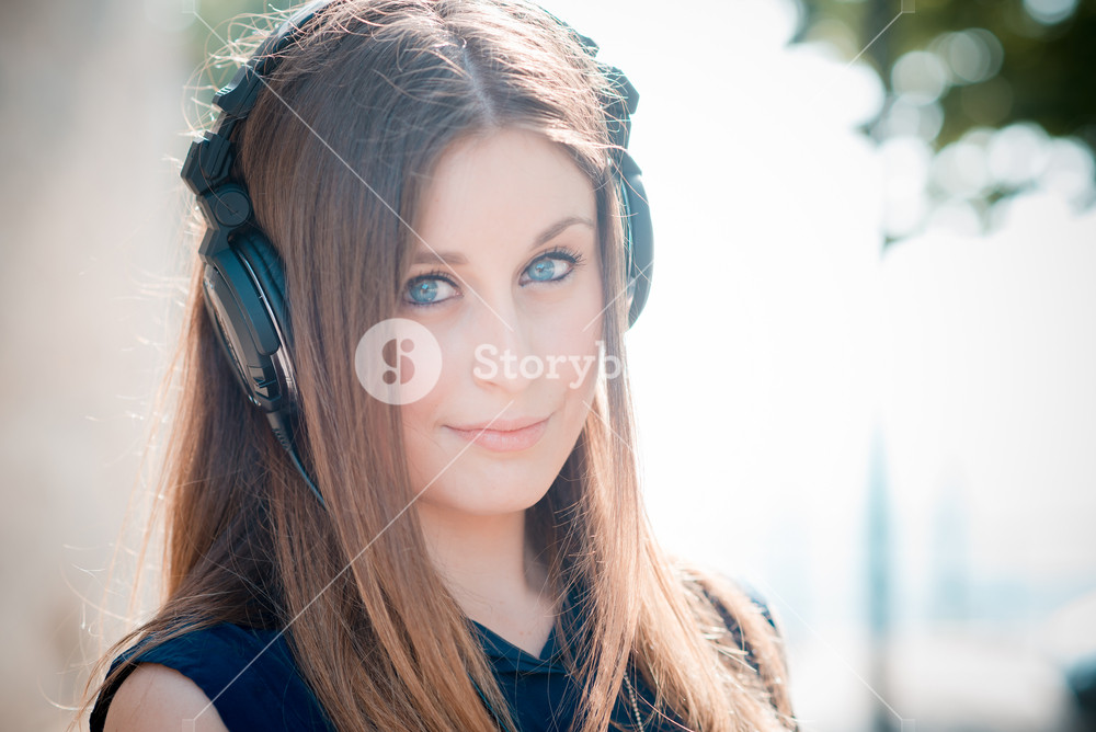 Stylish woman enjoying music with headphones in the city