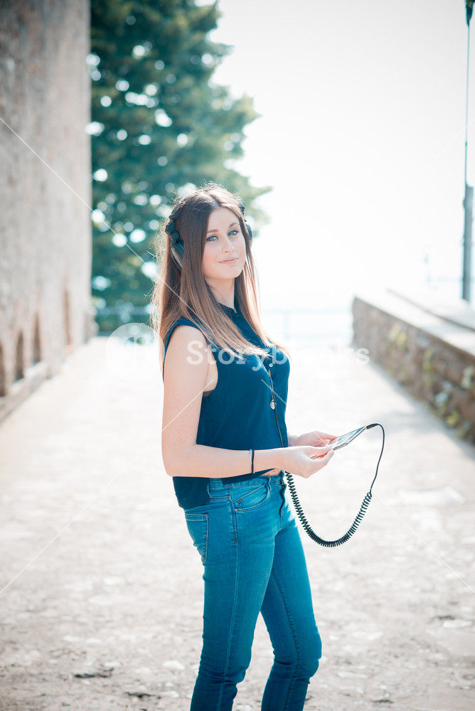 Stylish woman enjoying music with headphones in the city
