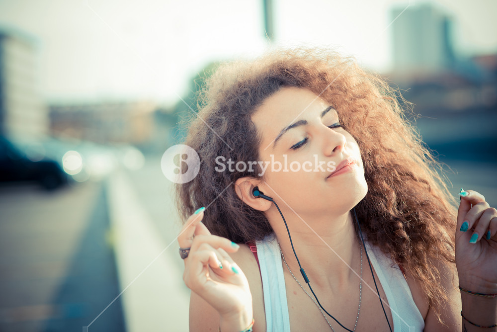Stylish woman enjoying music with tablet in the city