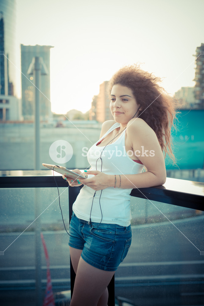 Stylish woman enjoying music with tablet in the city