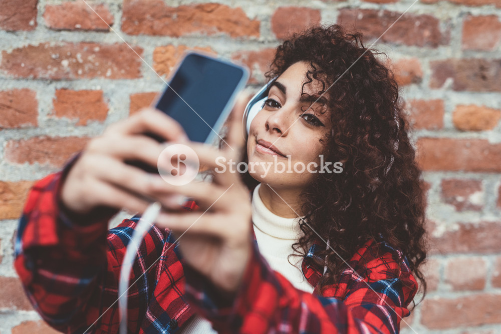 Young woman enjoying music and taking a selfie with her smartphone