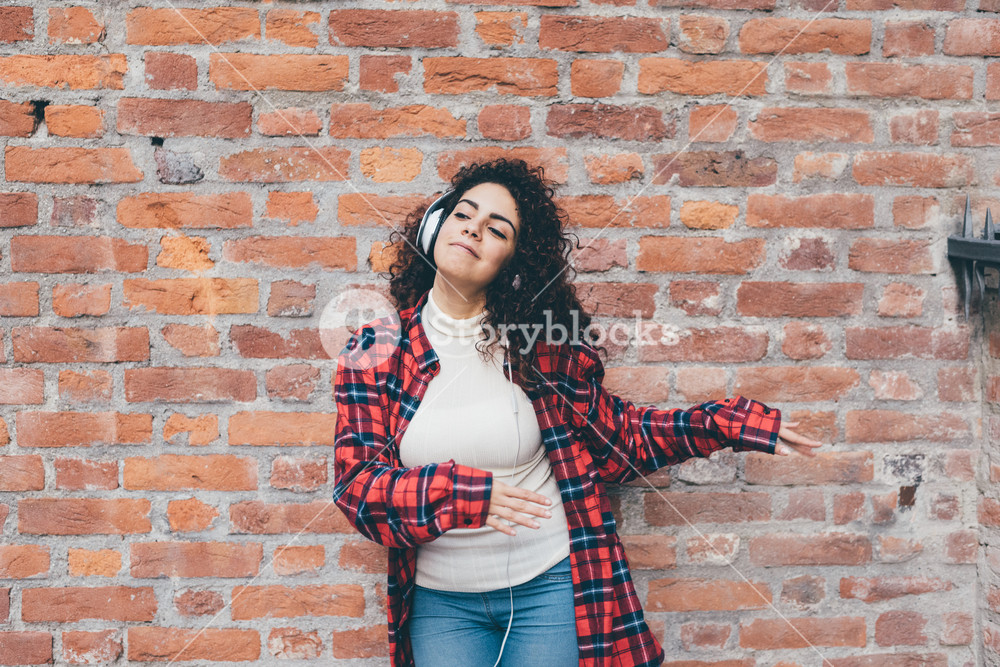 Young woman dancing outdoors in the city with headphones - freedom, enjoying, music concept